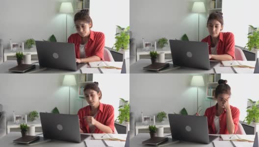 年轻的亚洲妇女坐在眼睛闭从疲惫和疲倦在工作在家庭办公室使用笔记本电脑。劳累过度的亚洲女学生工作人员，在电脑工作后因疲劳而按摩眼睛和太阳穴高清在线视频素材下载