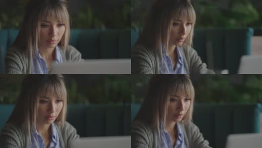 一位亚洲女性坐在那里，看着笔记本电脑屏幕，沉思着。他的脸上满是头脑风暴和焦虑。沉思的亚洲女人高清在线视频素材下载