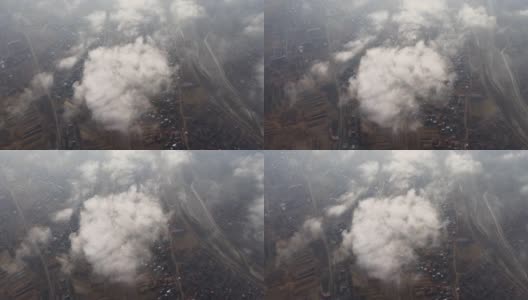 高空鸟瞰图，远处的城市被暴雨前形成的蓬松的积云所覆盖。飞机角度多云的景观高清在线视频素材下载