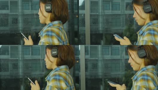 女士用手机听音乐。外面在下雨，侧视图。从右到左。高清在线视频素材下载