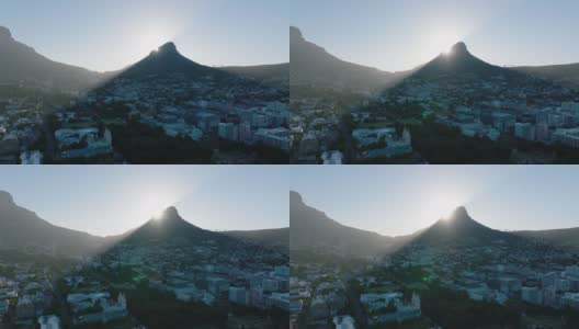 在住宅区高高的山顶后面升起的太阳。狮头山投下的影子在小镇上。南非开普敦高清在线视频素材下载