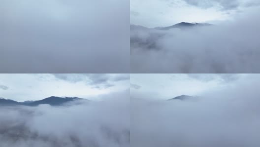 无人机在湖面上空的云层中飞行，露出了那座山。冬天的景色高清在线视频素材下载