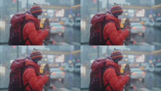 冬天，年轻的女游客在城市里用智能手机等待红绿灯高清在线视频素材下载