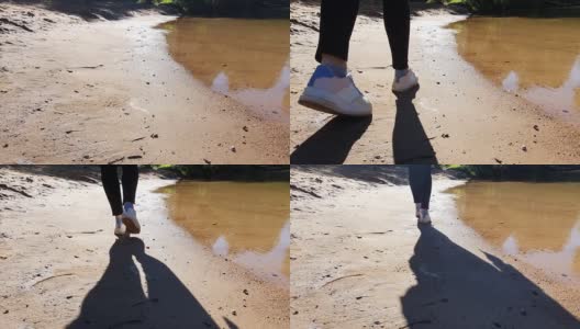 女人的腿在运动鞋的特写沿着沙河海滩散步高清在线视频素材下载