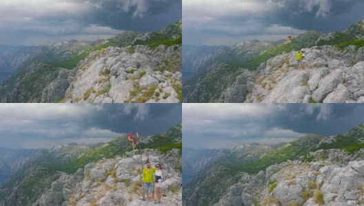 年轻的游客们站在山顶上，眺望着黑山科托尔湾的大海。空中无人机视图。生活方式和旅游理念。高清在线视频素材下载