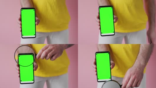 一名身穿白色牛仔裤和黄色t恤的男子展示了一个绿色智能手机屏幕，并将放大镜移到屏幕上。模拟。粉色背景,特写。搜索和广告的概念高清在线视频素材下载