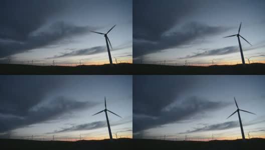 旋转的风力涡轮机，草地，日落时的天空，实时。高清在线视频素材下载