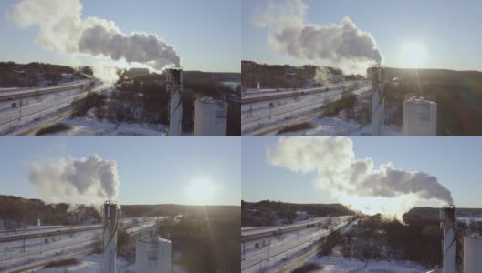在一个阳光明媚的冬日里，瑞典斯堪的那维亚，发电厂的烟囱里飘着污染的烟雾，以火车和高速公路为背景发电高清在线视频素材下载