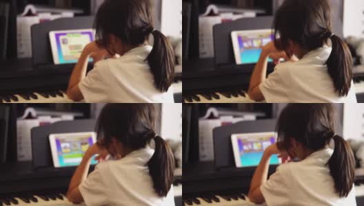 一个亚洲女孩正在用平板电脑上在线音乐钢琴课。高清在线视频素材下载