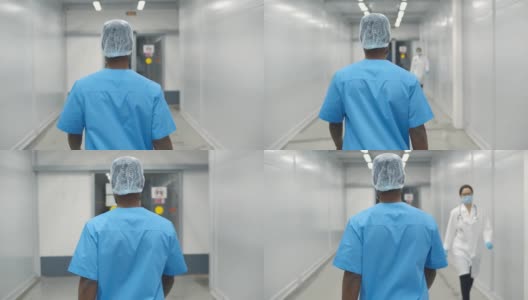 非裔美国男外科医生走过医院走廊的后视图。男护士穿着手术服，戴着帽子走在诊所走廊上。医学与健康理念高清在线视频素材下载