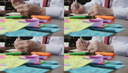 在办公室里，一只手用钢笔在记事本上写字的特写。高清在线视频素材下载