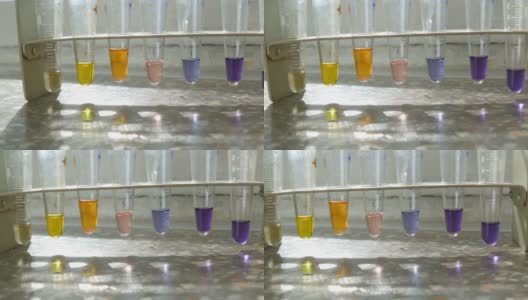 医学试管在实验室与彩色液态水在实验室与试剂的窗口与大理石窗台。高清在线视频素材下载