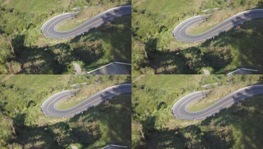 鸟瞰汽车在森林里的乡村道路上行驶。电影无人机拍摄飞行在乡村公路与弯曲的山。高清在线视频素材下载