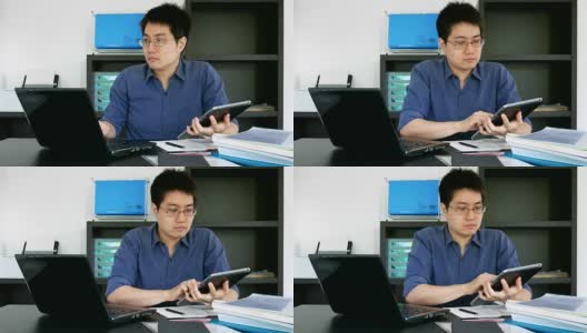 戴眼镜的亚洲商人在家庭办公室使用笔记本电脑和平板电脑高清在线视频素材下载