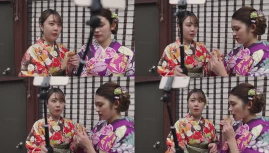 穿着和服的年轻女性朋友为了拍视频而吃街头小吃高清在线视频素材下载