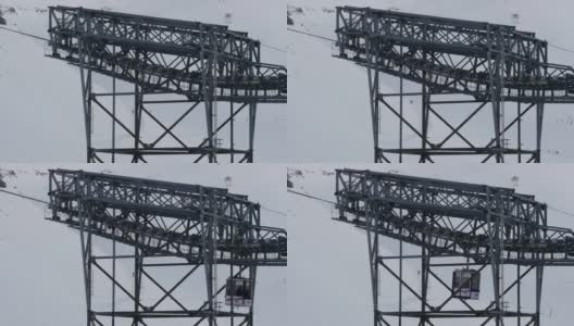 巨大的金属柱子从缆车下经过，缆车位于滑雪者下坡的斜坡顶部高清在线视频素材下载