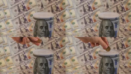 一名男子的手将1美元硬币放入一个印有100美元图案的储蓄罐中高清在线视频素材下载