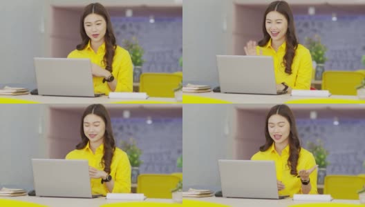 年轻快乐的亚洲商务女性穿着黄色衬衫，与她的业务团队在现代办公室或联合办公空间进行在线视频电话会议高清在线视频素材下载