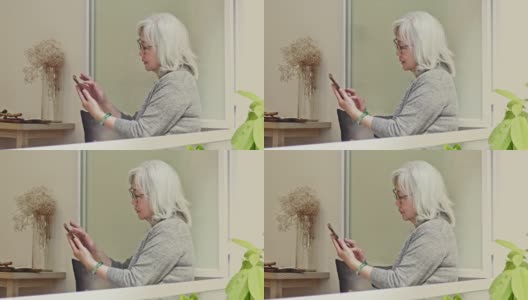 中国老年女性在咖啡馆里用智能手机放松高清在线视频素材下载