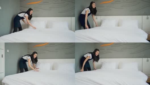 一个年轻的女仆带着医用口罩在酒店房间的床上更换床单。高清在线视频素材下载
