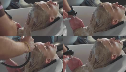 男发型师在现代美容院给一个金发女人洗头高清在线视频素材下载