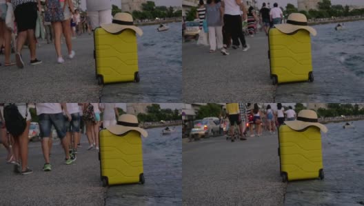 手提箱上戴着夏天的帽子，它在拥挤的海滨高清在线视频素材下载
