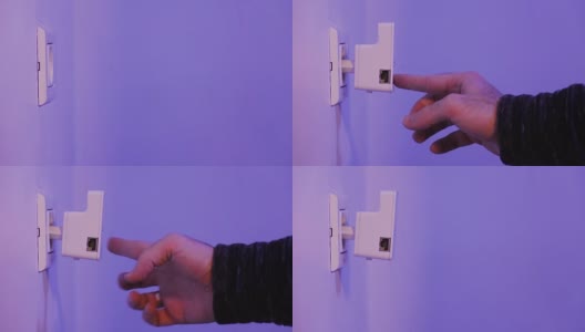 男子将WiFi中继器插入墙上的电源插座，然后用手指按WPS按钮高清在线视频素材下载
