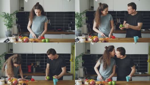 快乐的女人在厨房准备早餐，她的丈夫拿着苹果过来，向她表演杂耍，女人笑着，一个苹果掉了下来，夫妇俩在找苹果高清在线视频素材下载