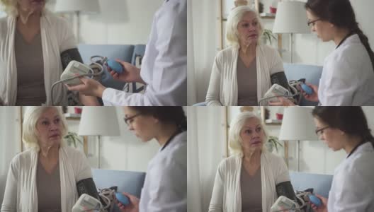 医生检查血压和来访的退休妇女在家高清在线视频素材下载