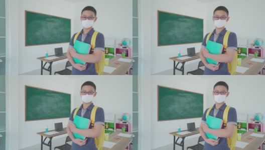 亚洲小学生男孩背着书包和书本戴上口罩，防止Covid - 19在教室里爆发，返校时重新开学，新常态的教育理念。高清在线视频素材下载