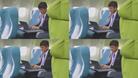 一位亚洲高管商人坐在商务舱，在飞机上用笔记本电脑工作。这个人很忙，眼睛感到很累。关注医疗保健和技术为商务人士的理念。高清在线视频素材下载
