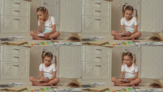 肖像小主要小女孩做家庭作业使用笔记本电脑坐在家里的地板上。高清在线视频素材下载