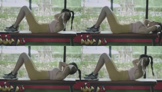 健身理念，美丽的亚洲女孩穿着运动服在健身房里做仰卧起坐。在健身训练中加强自己的腹部核心肌肉。健康的生活方式高清在线视频素材下载
