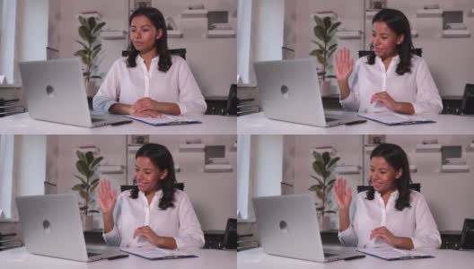 在现代办公室里，女商人在笔记本电脑屏幕前挥手，在桌子前说话高清在线视频素材下载