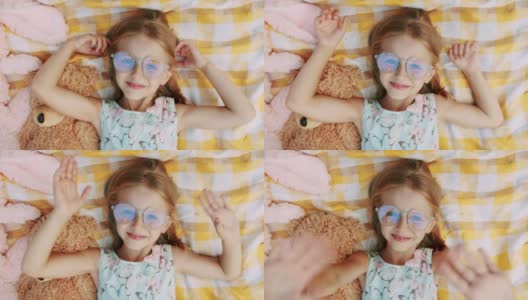 一个6-7岁的小女孩戴着眼镜，休息，用她的手问候高清在线视频素材下载