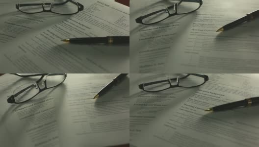 用钢笔、眼镜在办公桌上翻拍简历。高清在线视频素材下载
