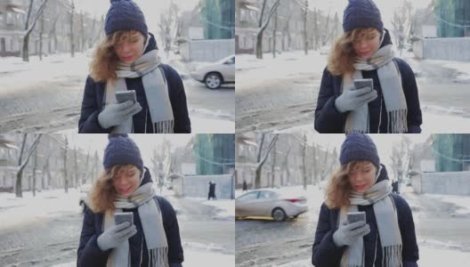 快乐的年轻女人戴着温暖的围巾和帽子在手机上打字和微笑在冬天在城市的道路附近的户外。高清在线视频素材下载