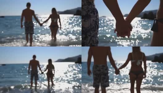 在阳光明媚的日子里，美丽的一对手牵着手走向大海。年轻夫妇花时间一起在夏季旅游。阳光反射在水面上的背景。近距离高清在线视频素材下载