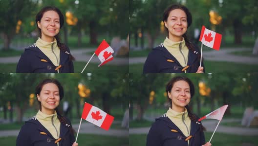 慢动作肖像迷人的女孩加拿大体育迷拿着加拿大国旗，看着镜头微笑。人与国的观念。高清在线视频素材下载
