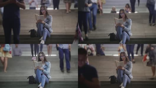 一个年轻女子坐在地铁的楼梯上看书高清在线视频素材下载
