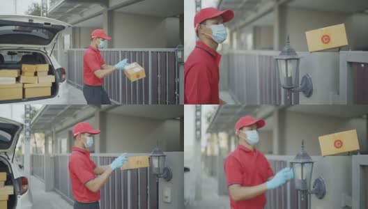 4 k慢动作视频。穿着红色制服的男性快递员寄包裹盒子喷上清洁酒精然后把包裹放在屋前的篱笆上。新标准的概念。高清在线视频素材下载