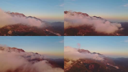 相机在云中移动。梦幻般的日出在岩石山顶上，看到雾气蒙蒙的山谷。高清在线视频素材下载