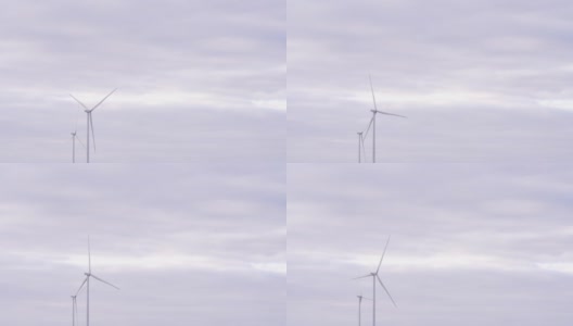 在海上或野外的大农场全速旋转叶片。旋转的风车在灰色的天空背景。由风力涡轮机产生的清洁可再生能源。另一种生活方式高清在线视频素材下载