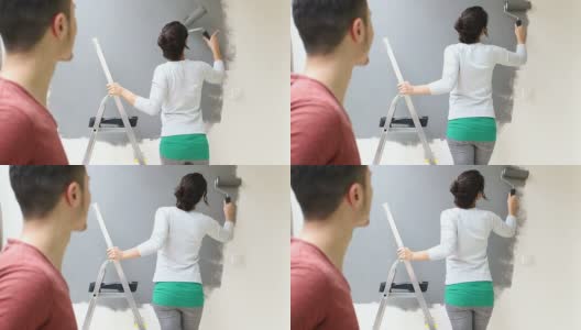 年轻的女人正在用油漆滚筒刷墙高清在线视频素材下载