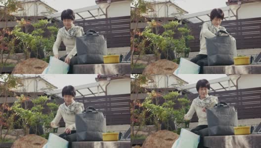 MLS-高级日本妇女添加土壤到一个家庭堆肥袋高清在线视频素材下载