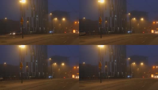 法国斯特拉斯堡——2021年11月6日:雾蒙蒙的秋夜城市，汽车驶过街道，行人和骑自行车的人走在路上高清在线视频素材下载