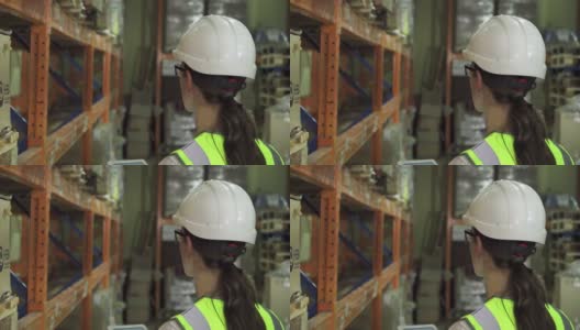 一名年轻的女工人穿着防护背心和头盔，穿过仓库高清在线视频素材下载
