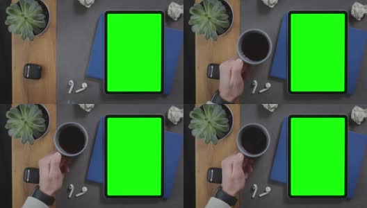 一名男子将一杯咖啡放在桌面上一个绿色屏幕的平板电脑旁边高清在线视频素材下载