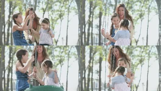 妈妈和两个女孩在公园玩，在轮胎秋千上高清在线视频素材下载