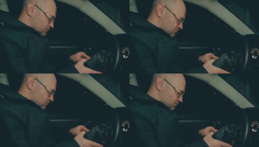 晚上，一位戴眼镜的沉思男子在车里往钱包里看高清在线视频素材下载